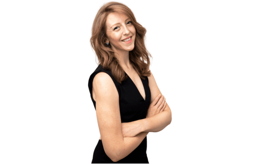 A woman with long hair wearing a black dress, smiling with arms crossed in front of her.