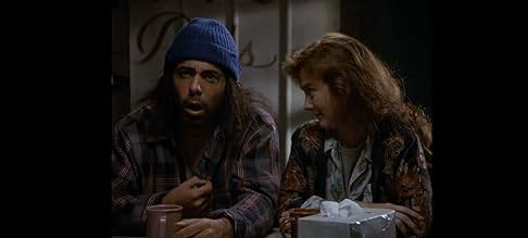 Two individuals sitting at a table, one wearing a blue beanie and plaid shirt, the other with curly hair and a patterned jacket.