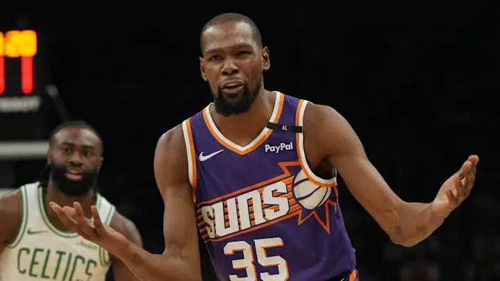 Kevin Durant wearing a Phoenix Suns jersey during a basketball game, gesturing towards the referee.