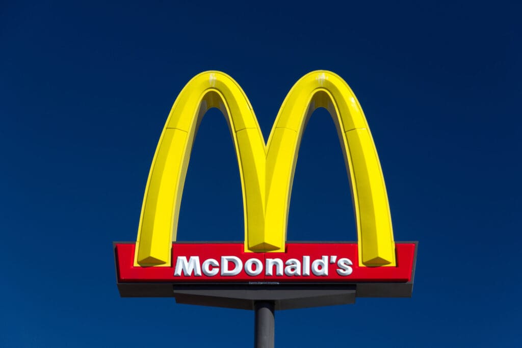 McDonald's sign featuring the iconic golden arches against a blue sky.