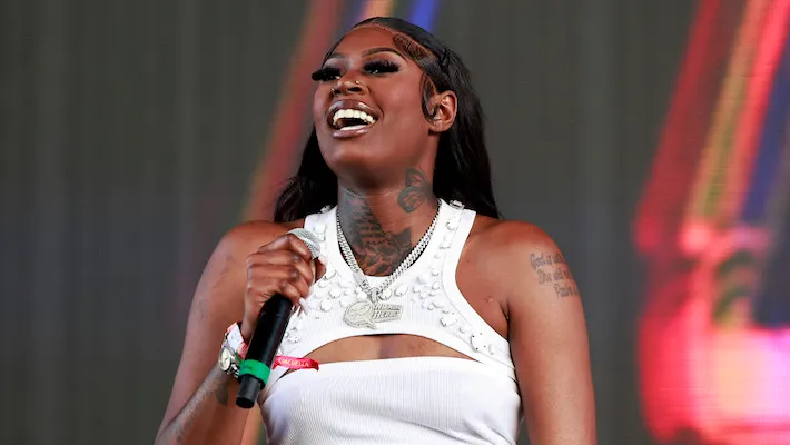 A female performer smiling while holding a microphone during a live performance.