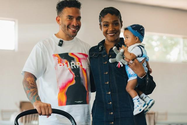 Tiffany Haddish posing with a child and a man, all smiling in a well-lit indoor space.